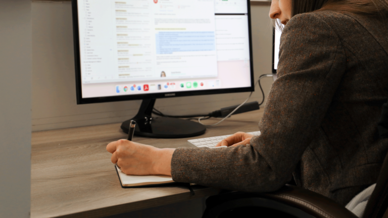 Head of client services sat at a desk writing in a notepad