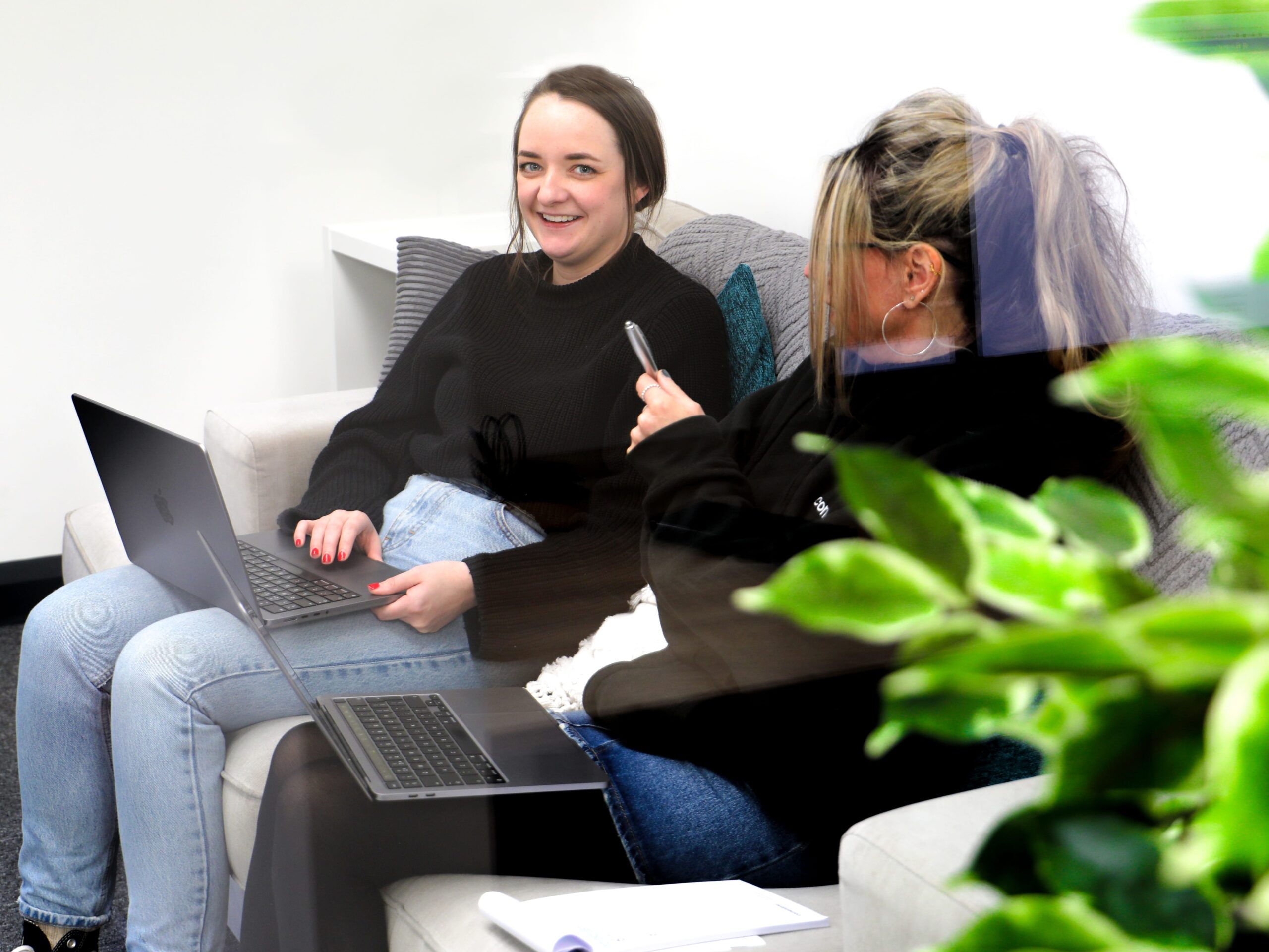 Two female team members at cornerstone working from a sofa at the cornerstone office