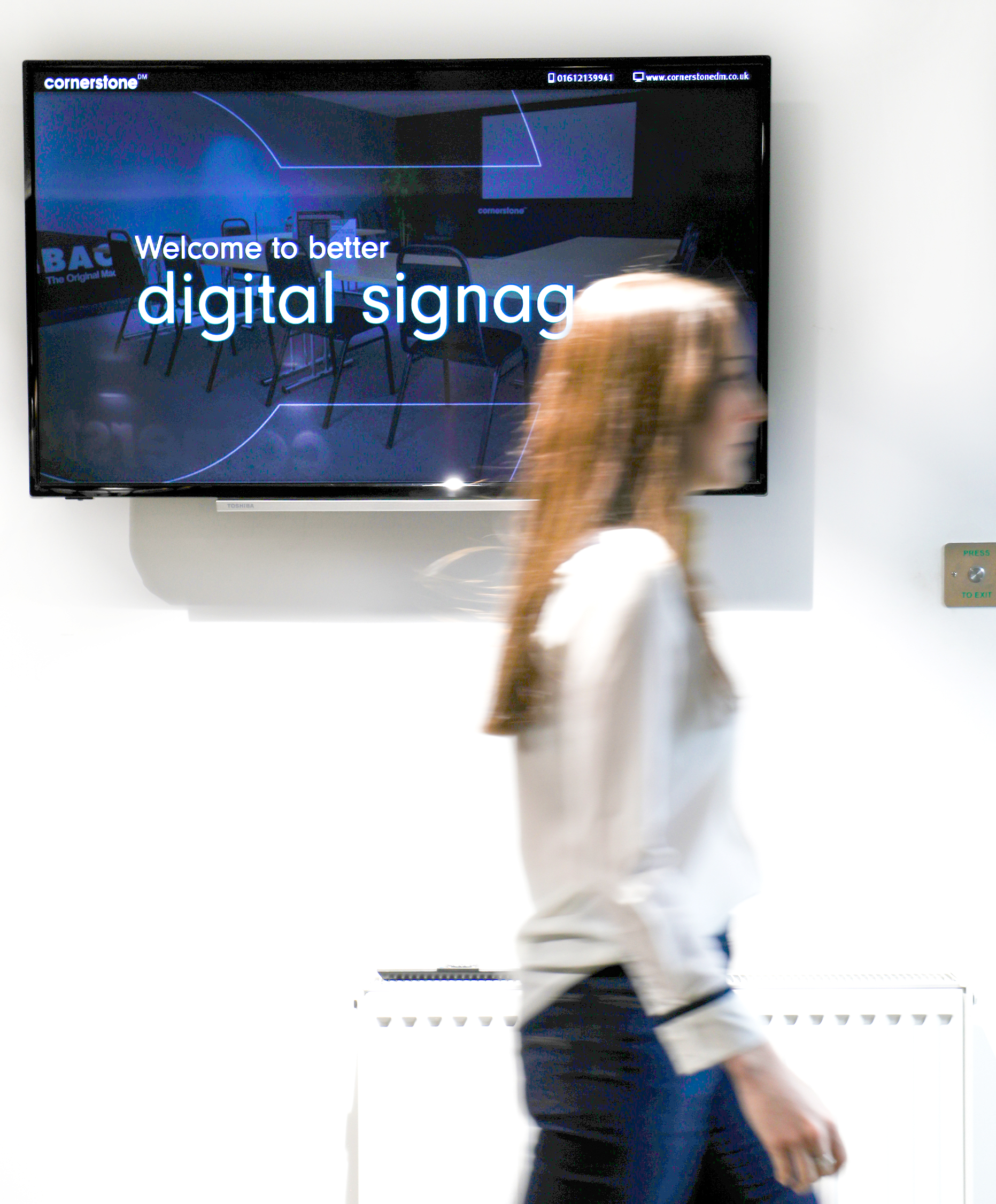 Cornerstone team member walking past a digital signage platform