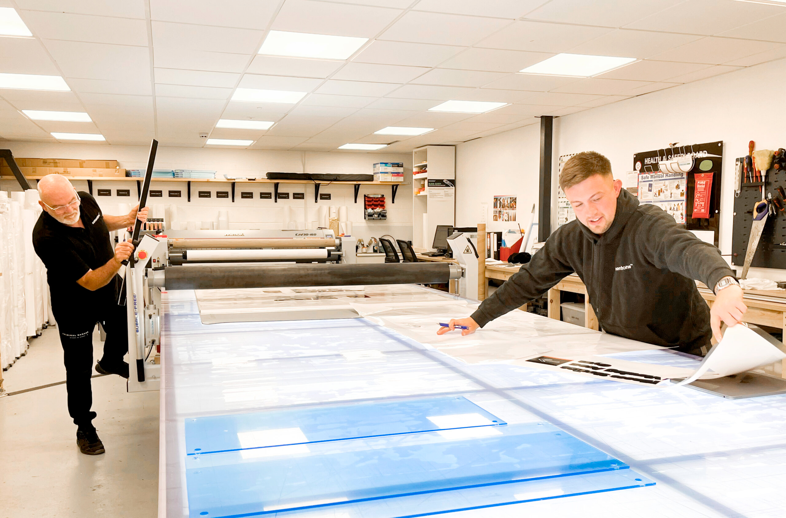 Wide format print production, showing Sam and Steve cutting down and mounting vinyl prints