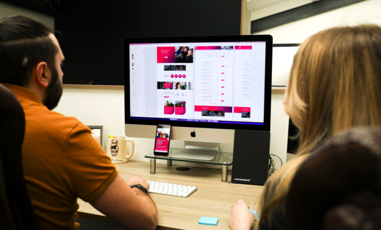 Two web designers at Cornerstone reviewing the Yes Manchester website design on screen