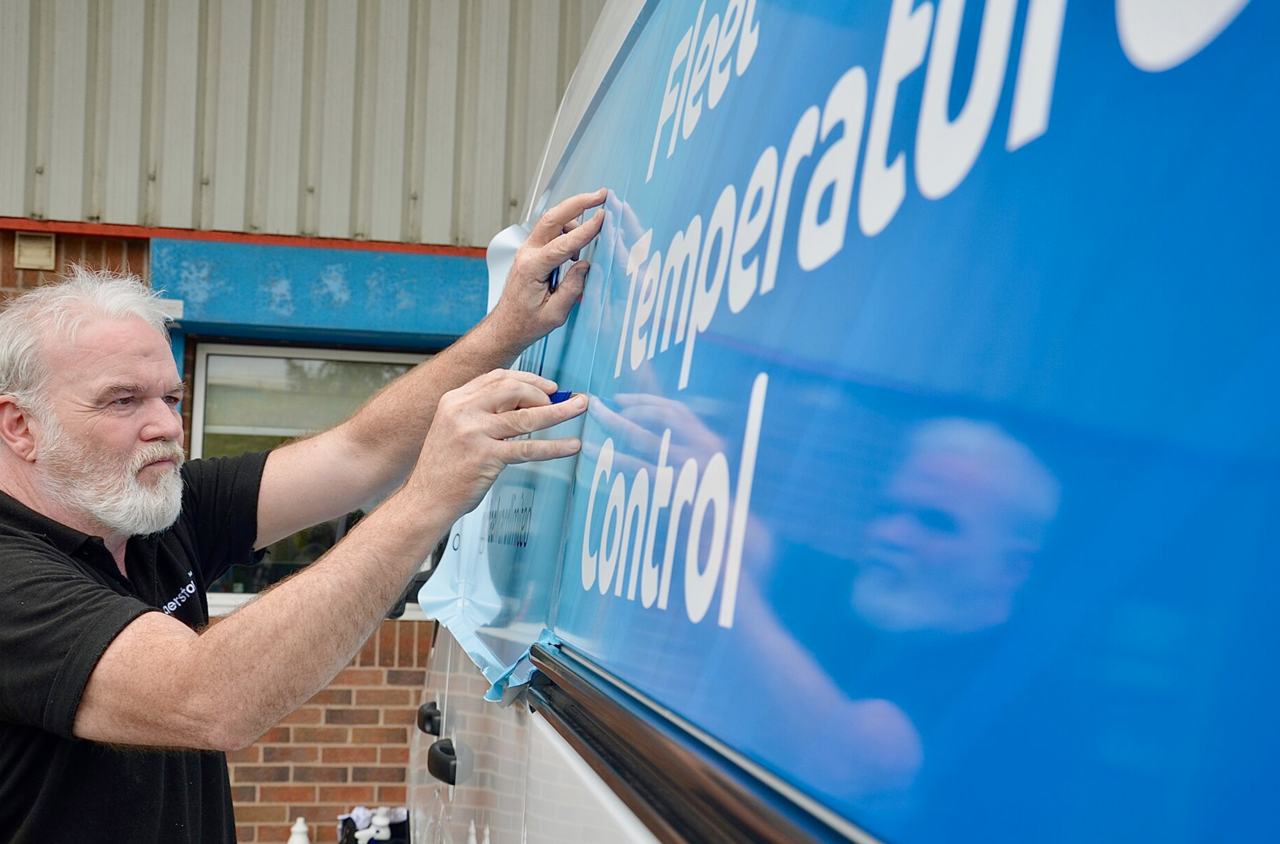 Steve applying vinyl signage to one of our clients vans